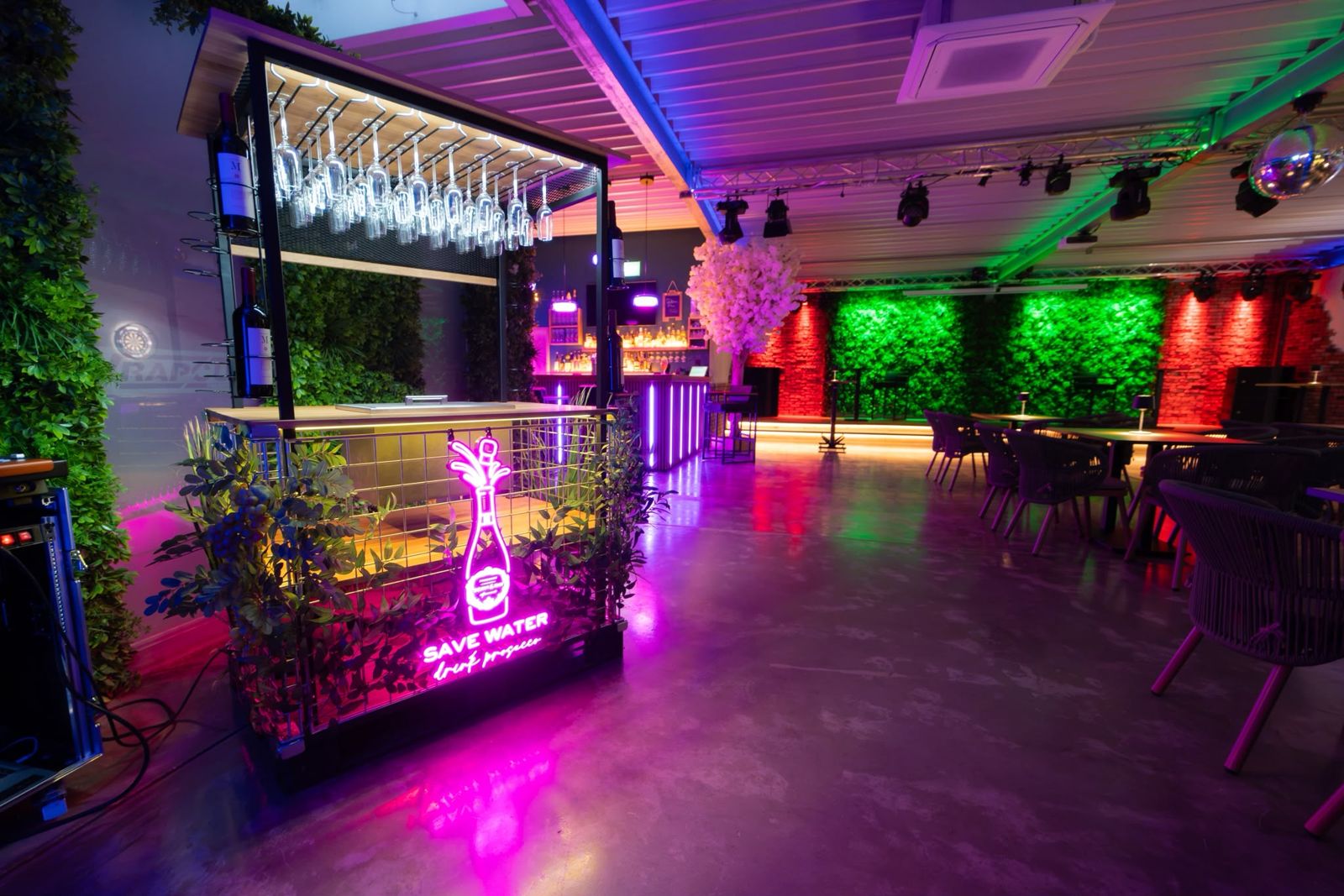Mobile Bar mit Neonschild vor Mooswänden und Ziegeloptik
