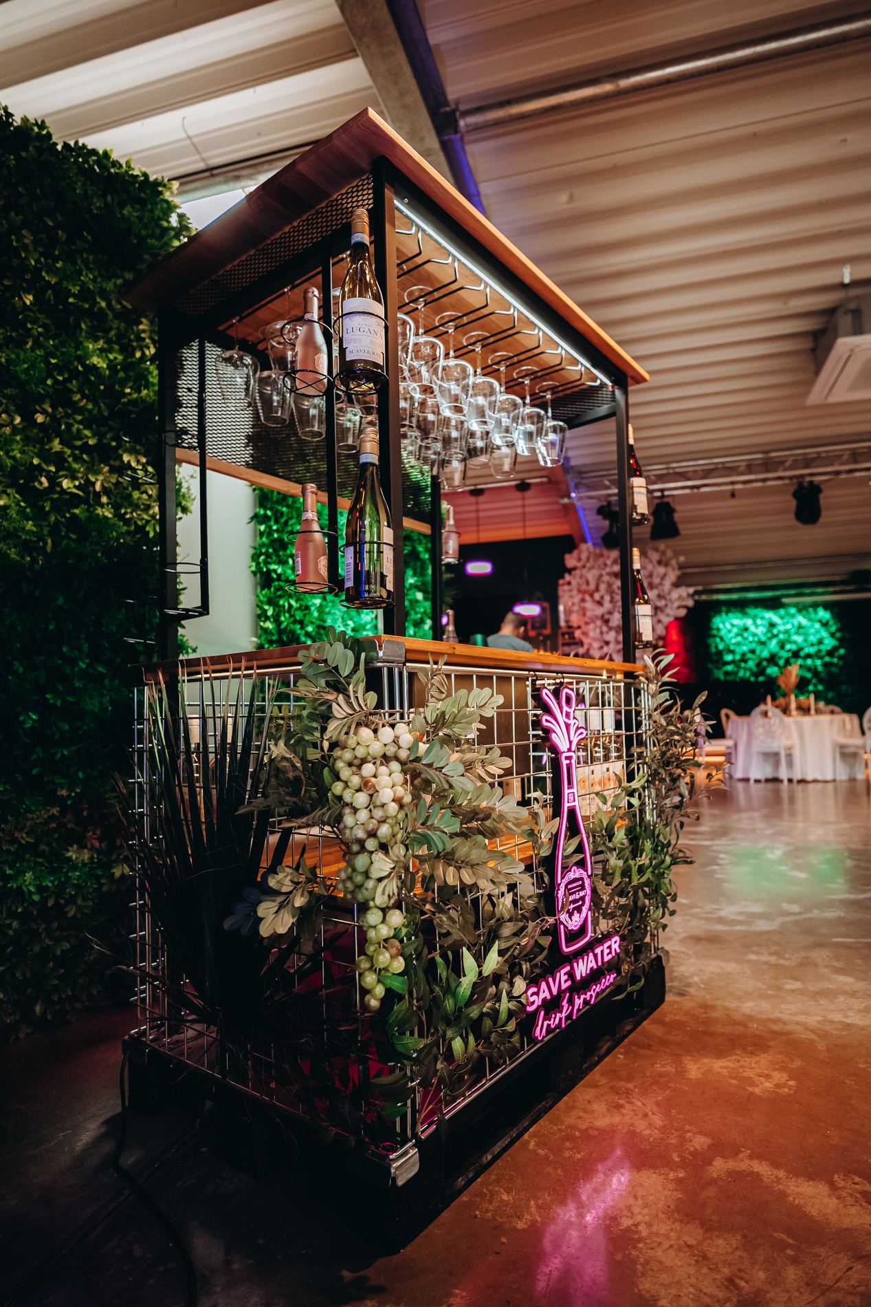 Begrünte Bar mit Neonschriftzug in der kleinen Eventlocation