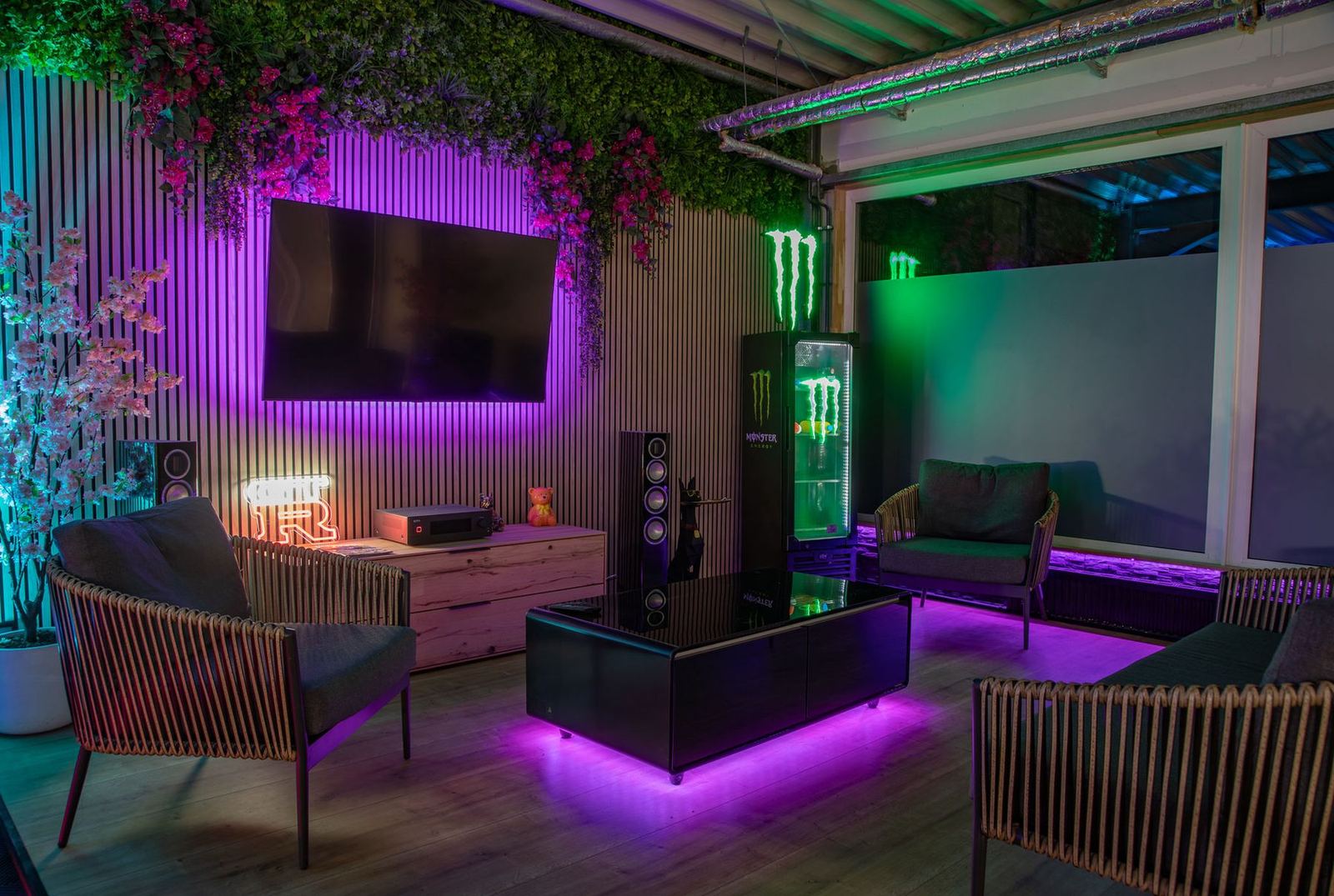 Lounge-Bereich mit Sofas, Großbildschirm und grüner Pflanzenwand