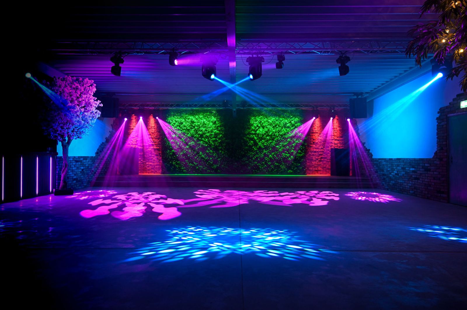 Eventlocation im Autowerk mit Mooswänden und blau-violetter Lichtstimmung