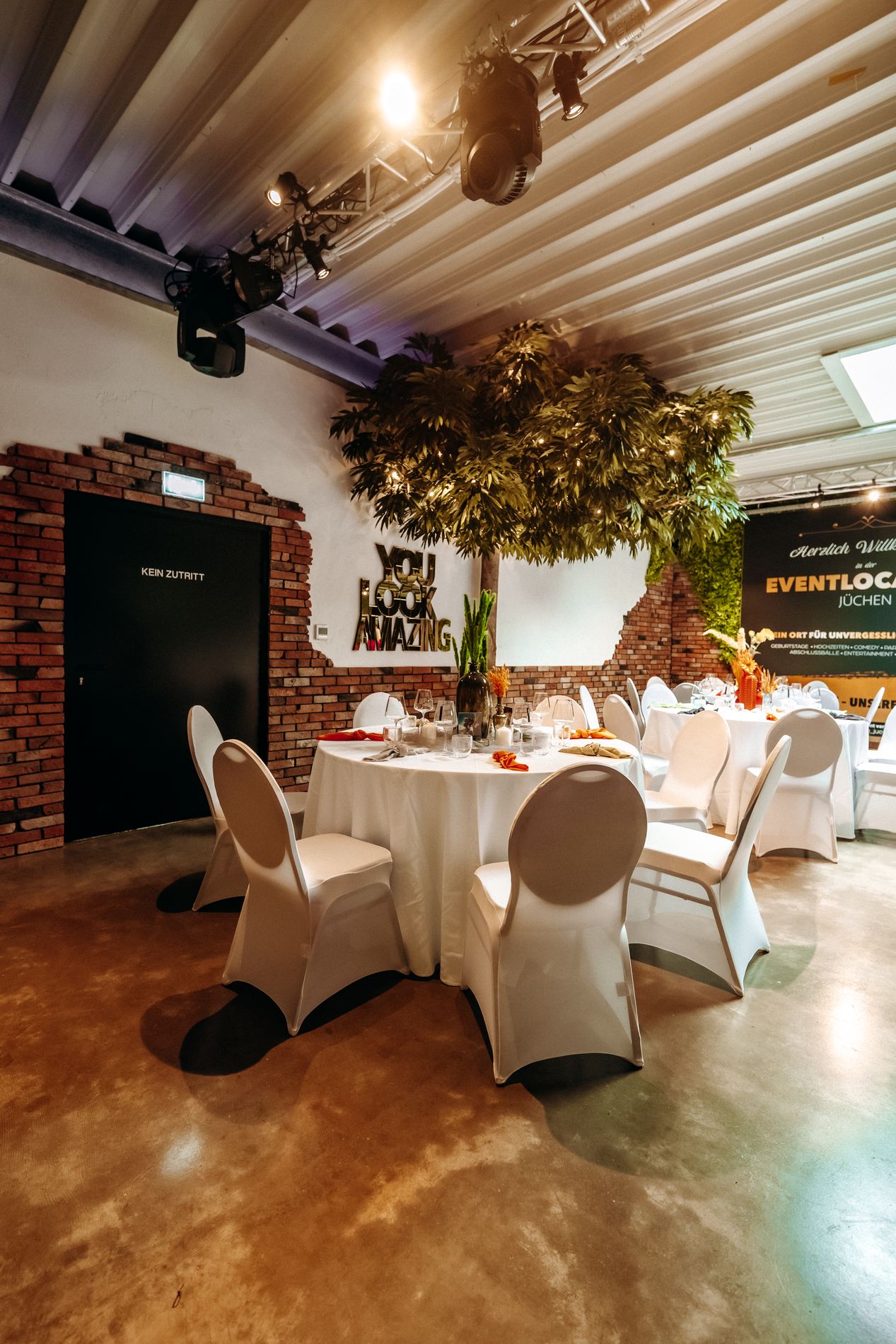 Großer Saal mit Rundtischen und beleuchteter Bühnenwand