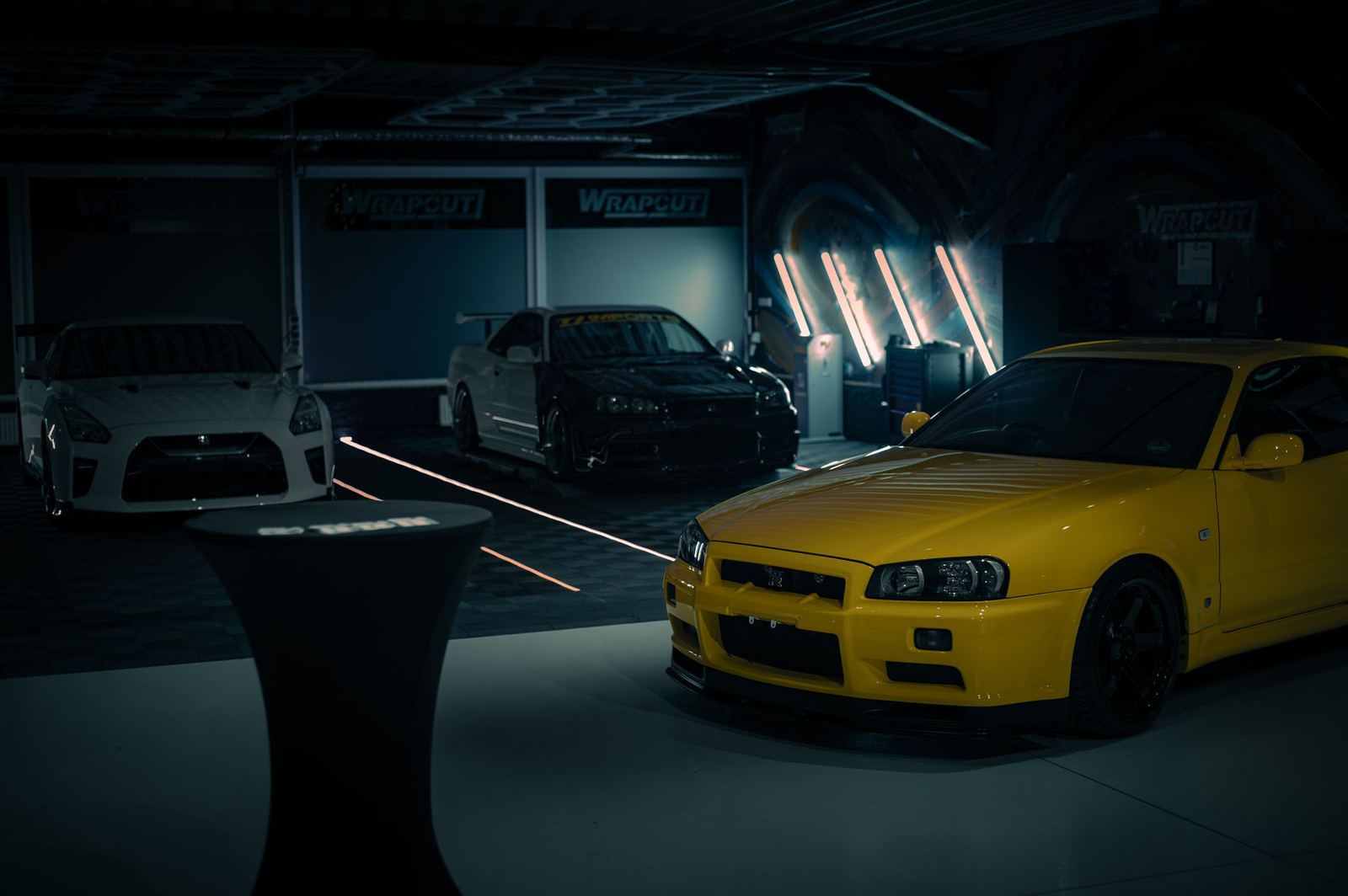 Stehtisch im Showroom vor gelbem Nissan Skyline R34